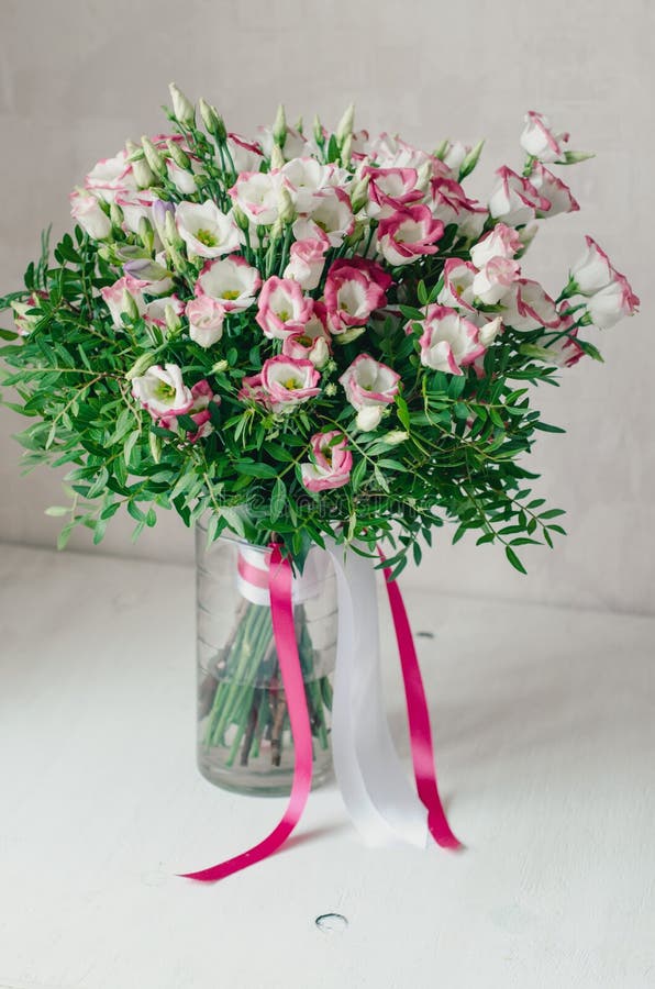 El ramo romántico hermoso de eustoma rosado y blanco florece con la cinta del satén en un florero en un fondo blanco imagen de archivo libre de regalías El ramo romántico hermoso de eustoma rosado y blanco florece con la cinta del satén en un florero en un fondo blanco imagen de archivo libre de regalías