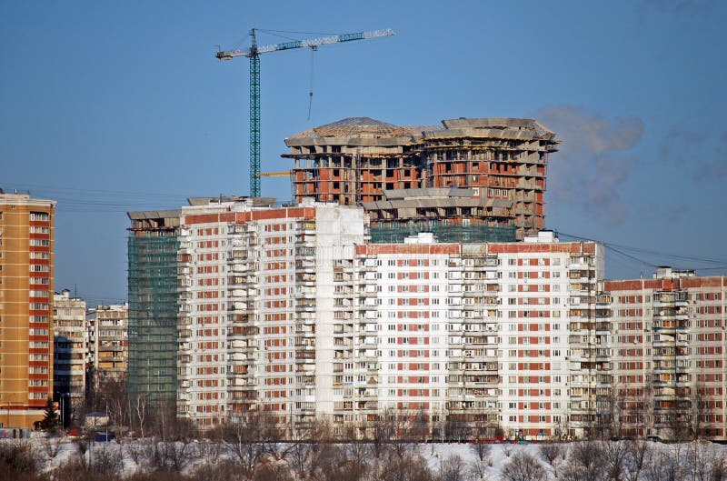 El rascacielos habitado con grúa contra la perspectiva del edificio de varios pisos viejo está bajo construcción fotos de archivo libres de regalías El rascacielos habitado con grúa contra la perspectiva del edificio de varios pisos viejo está bajo construcción fotos de archivo libres de regalías