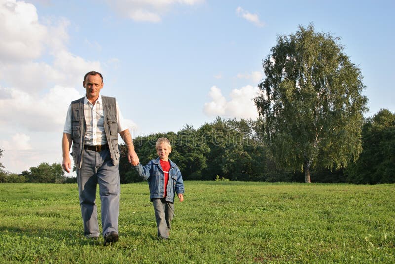 Grandfather and boy walking on meadow. Grandfather and boy walking on meadow