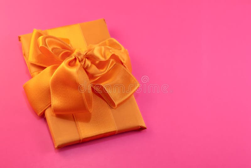 El regalo se embala y se adorna con un arco amarillo en un fondo rosado con el espacio de la copia Endecha plana, visión superior imágenes de archivo libres de regalías El regalo se embala y se adorna con un arco amarillo en un fondo rosado con el espacio de la copia Endecha plana, visión superior imágenes de archivo libres de regalías