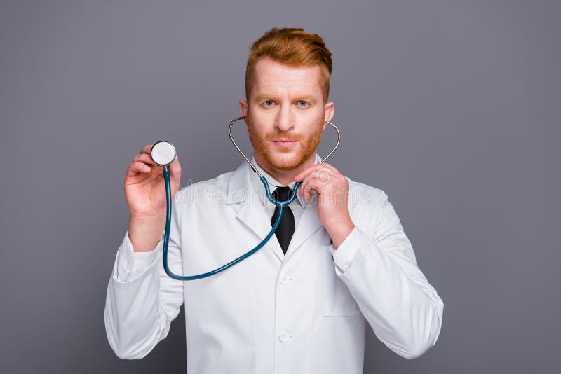 El retrato ascendente cercano del doctor atractivo sostiene el estetoscopio en oídos imagen de archivo libre de regalías El retrato ascendente cercano del doctor atractivo sostiene el estetoscopio en oídos imagen de archivo libre de regalías