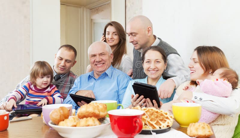 La familia multigeneración feliz utiliza los dispositivos electrónicos fotos de archivo La familia multigeneración feliz utiliza los dispositivos electrónicos fotos de archivo