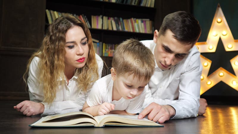 El retrato de la mam? joven de la familia, el hijo y el pap? est?n leyendo un libro juntos foto de archivo El retrato de la mam? joven de la familia, el hijo y el pap? est?n leyendo un libro juntos foto de archivo