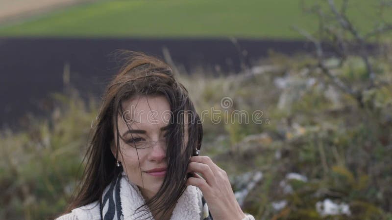 El retrato de la muchacha linda en la naturaleza corrige su pelo móvil lentamente