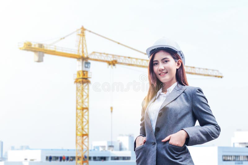 El retrato de la mujer joven hermosa del ingeniero lleva un casco de seguridad blanco que sonríe con el compromiso al éxito en el foto de archivo El retrato de la mujer joven hermosa del ingeniero lleva un casco de seguridad blanco que sonríe con el compromiso al éxito en el foto de archivo