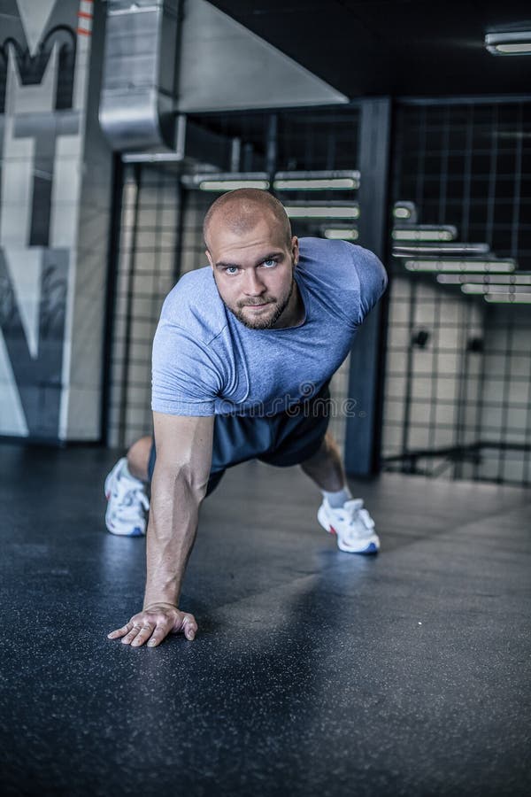 El retrato de un hombre hermoso que hace pectorales ejercita con una mano en gimnasio de la aptitud vestido en un uniforme de los foto de archivo El retrato de un hombre hermoso que hace pectorales ejercita con una mano en gimnasio de la aptitud vestido en un uniforme de los foto de archivo