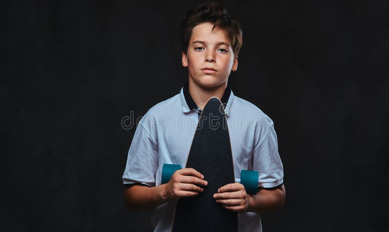 El retrato de un muchacho joven del patinador vistió en controles de una camiseta del blanco un longboard Aislado en el fondo osc fotos de archivo libres de regalías El retrato de un muchacho joven del patinador vistió en controles de una camiseta del blanco un longboard Aislado en el fondo osc fotos de archivo libres de regalías