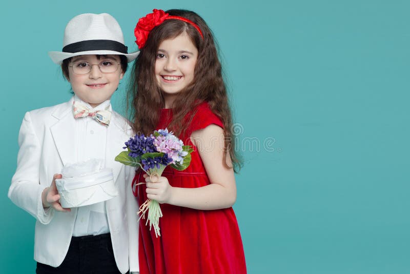 El retrato de un muchacho y de una muchacha encantadores que llevan en el traje blanco y el vestido rojo, presenta en el estudio, imagen de archivo libre de regalías El retrato de un muchacho y de una muchacha encantadores que llevan en el traje blanco y el vestido rojo, presenta en el estudio, imagen de archivo libre de regalías