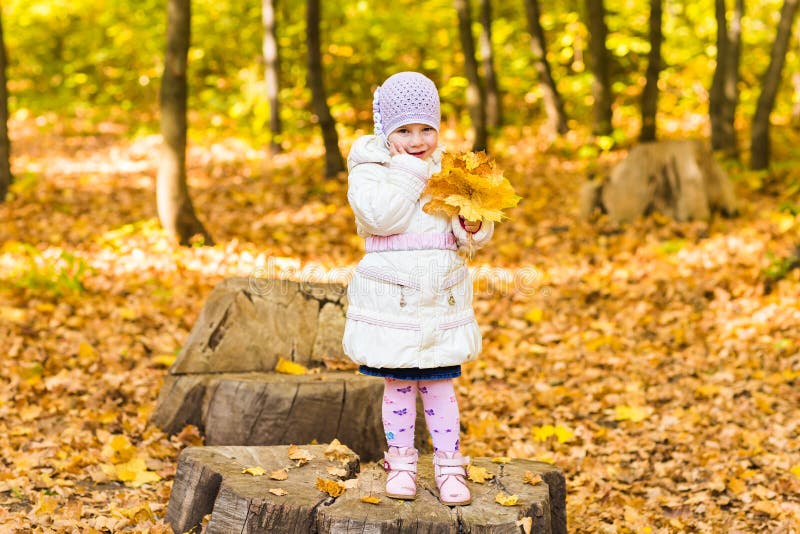 El retrato del pequeño bebé feliz que juega con otoño amarillo hojea en el fondo natural del parque del aire libre