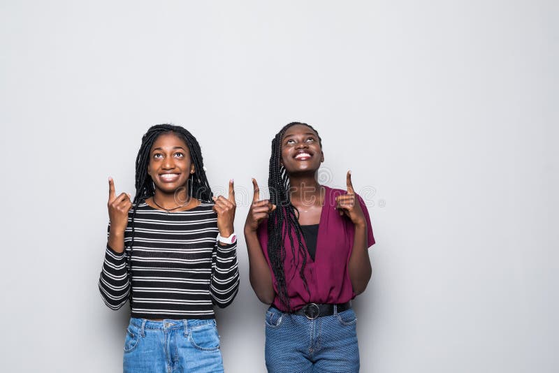 El retrato del pozo emocionado del africano dos vistió a las mujeres que señalaban los fingeres para arriba aislados sobre el fon fotos de archivo libres de regalías