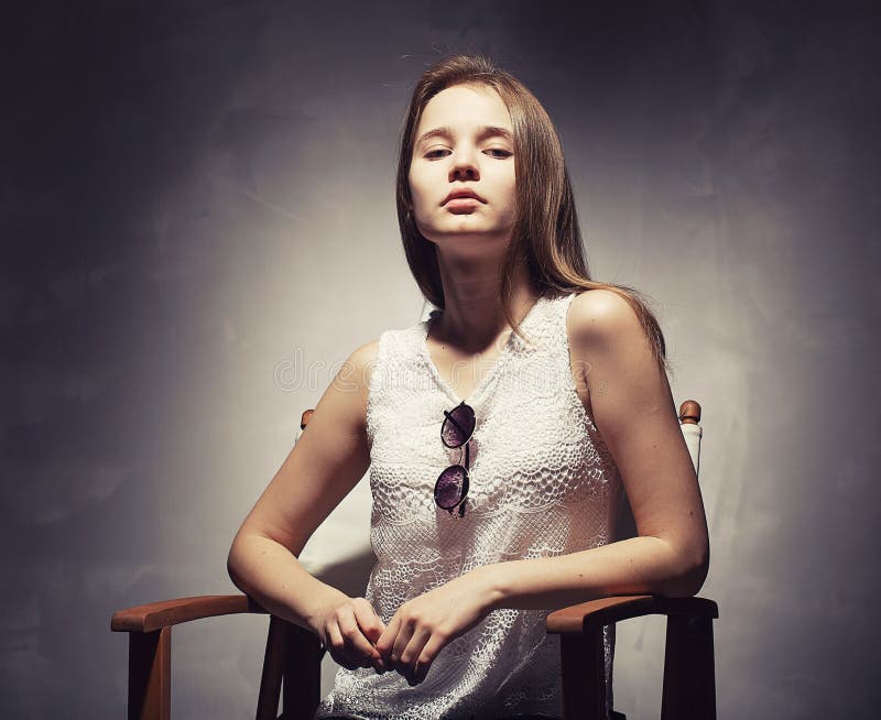 El retrato hermoso joven de la mujer del inconformista en vidrios y la ropa hecha punto acercan al vintage de la pared del graner foto de archivo El retrato hermoso joven de la mujer del inconformista en vidrios y la ropa hecha punto acercan al vintage de la pared del graner foto de archivo