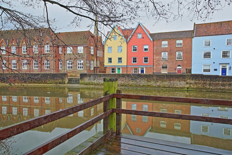 El río Wensum de la orilla con reflexiones de las casas coloridas y la torre y el chapitel de la catedral fotos de archivo El río Wensum de la orilla con reflexiones de las casas coloridas y la torre y el chapitel de la catedral fotos de archivo