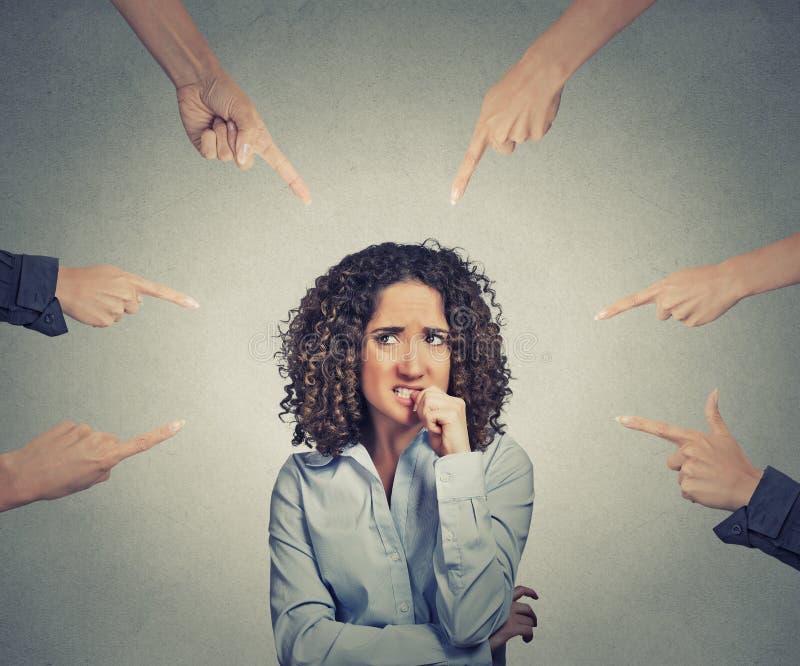 Concept of social accusation of guilty businesswoman many fingers pointing at on grey office wall background. Portrait scared anxious embarrassed woman biting fingernails. Concept of social accusation of guilty businesswoman many fingers pointing at on grey office wall background. Portrait scared anxious embarrassed woman biting fingernails