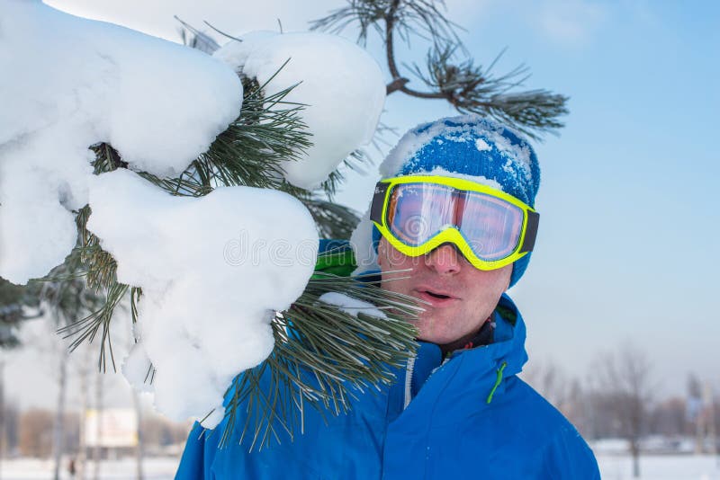 El snowboarder alegre en gafas del sol se está colocando por otra parte con nieve foto de archivo El snowboarder alegre en gafas del sol se está colocando por otra parte con nieve foto de archivo