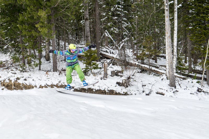 El Snowboarder que salta en las montañas en un fondo del bosque fotos de archivo El Snowboarder que salta en las montañas en un fondo del bosque fotos de archivo