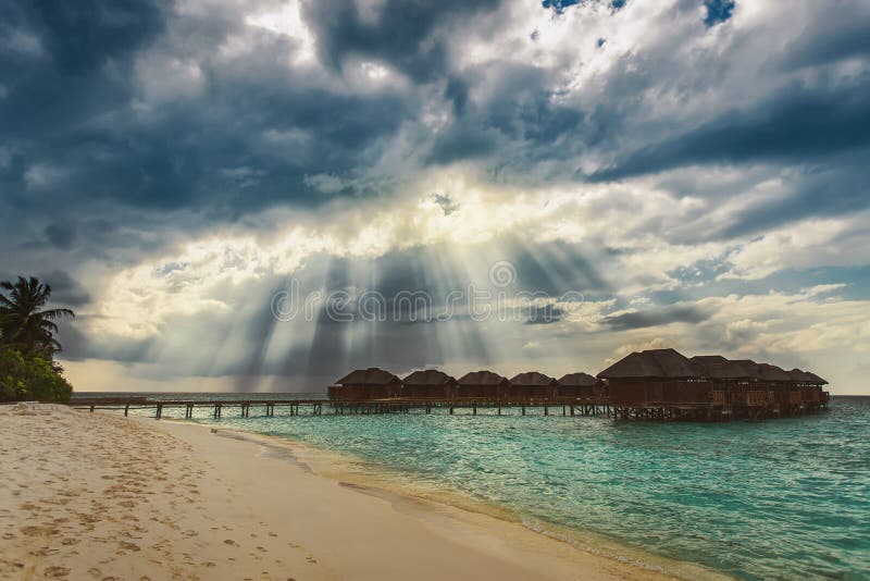 El sol del cielo irradia sobre casas de planta baja del agua en la isla tropical fotos de archivo libres de regalías El sol del cielo irradia sobre casas de planta baja del agua en la isla tropical fotos de archivo libres de regalías