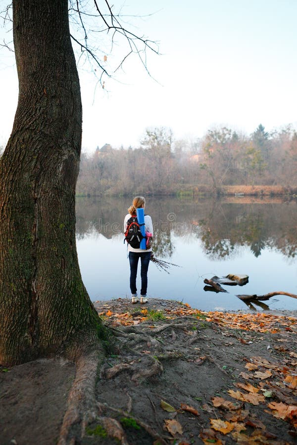 El soporte del caminante de la mujer y se relaja en el riverbank foto de archivo El soporte del caminante de la mujer y se relaja en el riverbank foto de archivo
