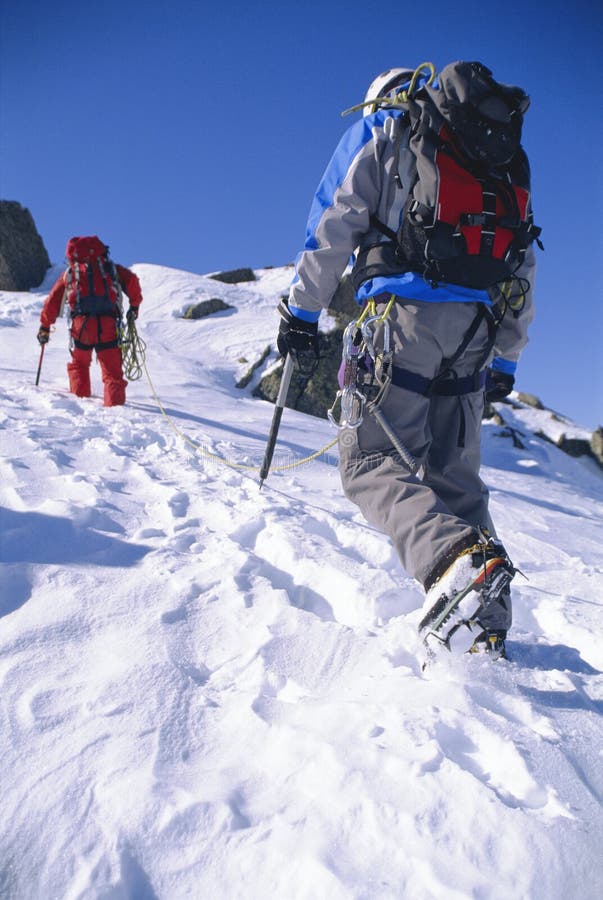 El subir de montaña de los hombres jovenes en pico nevoso