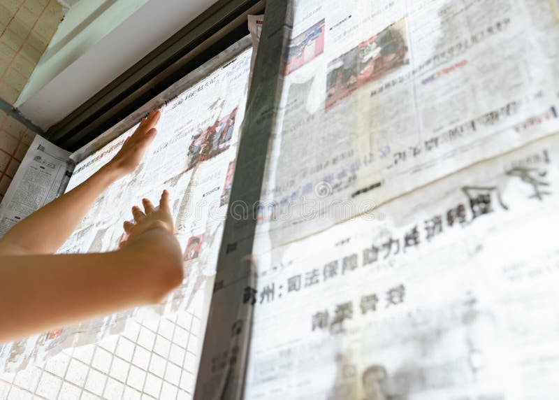 El tifón estupendo Mangkhut va a China y a una señora que pega el periódico a las ventanas de cristal para reforzarlas fotografía de archivo libre de regalías El tifón estupendo Mangkhut va a China y a una señora que pega el periódico a las ventanas de cristal para reforzarlas fotografía de archivo libre de regalías