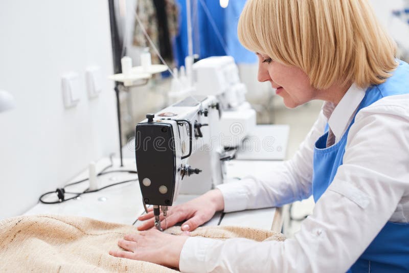 El trabajador del lavadero realiza la reparación de la ropa en la máquina de coser fotos de archivo libres de regalías El trabajador del lavadero realiza la reparación de la ropa en la máquina de coser fotos de archivo libres de regalías