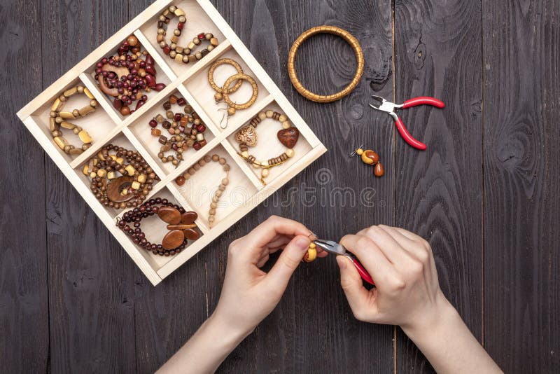 El trabajo hecho a mano en casa, la muchacha hace las manos de la joyería en la tabla imagen de archivo libre de regalías El trabajo hecho a mano en casa, la muchacha hace las manos de la joyería en la tabla imagen de archivo libre de regalías