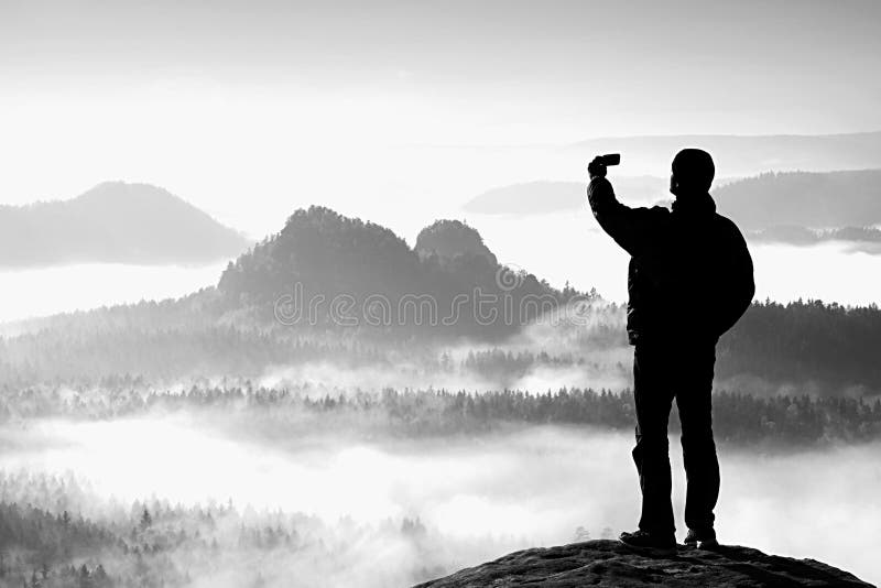 El turista alto está tomando el selfie en pico sobre el valle Fotografía elegante del teléfono imagenes de archivo El turista alto está tomando el selfie en pico sobre el valle Fotografía elegante del teléfono imagenes de archivo