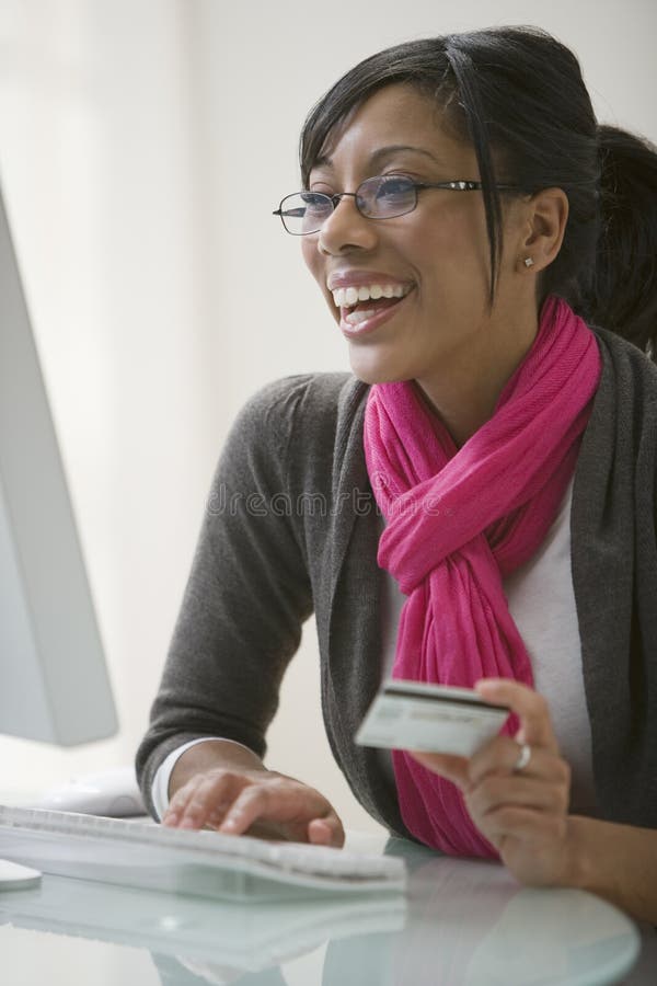 El usar de la mujer negra de la tarjeta de crédito para el comercio electrónico fotografía de archivo El usar de la mujer negra de la tarjeta de crédito para el comercio electrónico fotografía de archivo