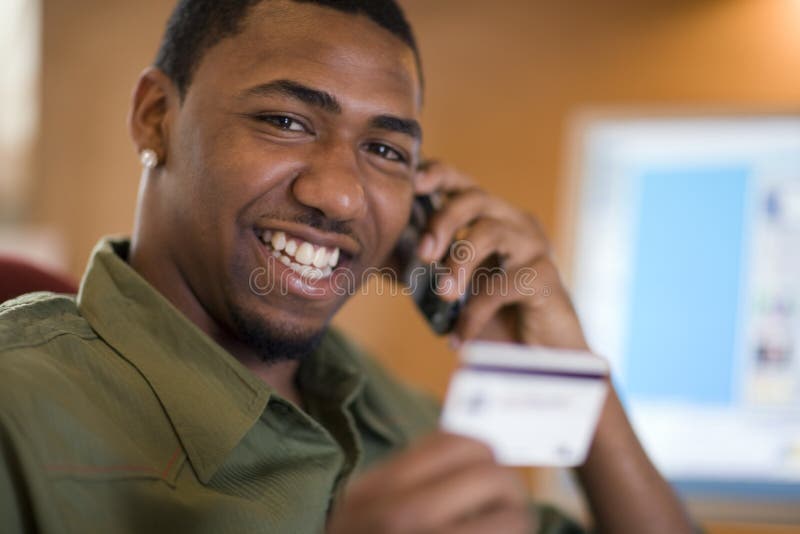 El usar del hombre de la tarjeta de crédito y teléfono celular fotografía de archivo libre de regalías El usar del hombre de la tarjeta de crédito y teléfono celular fotografía de archivo libre de regalías