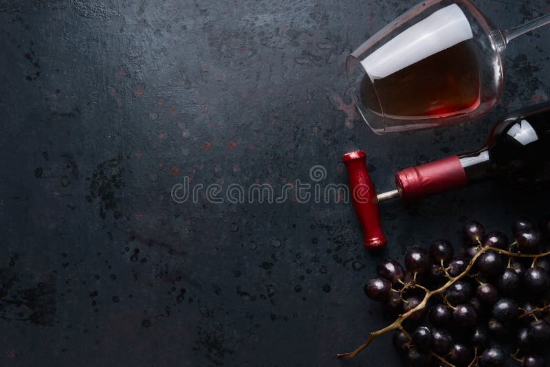 El vidrio con el vino rojo, la botella con el sacacorchos y la uva roja se agrupa en el fondo rústico negro, visión superior luga imagenes de archivo El vidrio con el vino rojo, la botella con el sacacorchos y la uva roja se agrupa en el fondo rústico negro, visión superior luga imagenes de archivo
