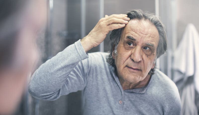 El viejo hombre está comprobando pérdida de pelo foto de archivo libre de regalías El viejo hombre está comprobando pérdida de pelo foto de archivo libre de regalías