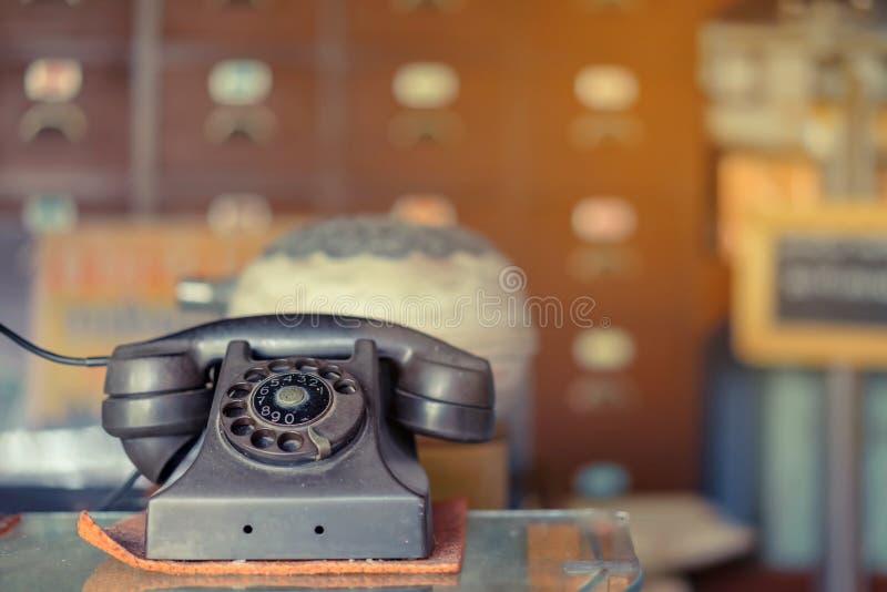 El viejo teléfono negro con dial rotatorio con polvo y arañazos colocados en una vitrina transparente fotografía de archivo El viejo teléfono negro con dial rotatorio con polvo y arañazos colocados en una vitrina transparente fotografía de archivo