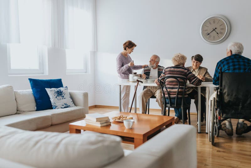 El voluntario ayuda a las personas mayores que viven en un hogar de acogida imagen de archivo libre de regalías
