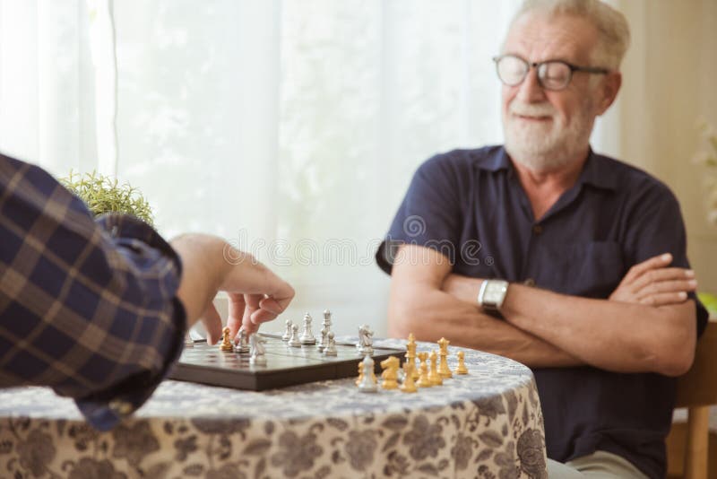 Elder inteligente jugando al juego de tablero de ajedrez en casa para entrenar la memoria del cerebro y pensar feliz sonriente en imagen de archivo libre de regalías Elder inteligente jugando al juego de tablero de ajedrez en casa para entrenar la memoria del cerebro y pensar feliz sonriente en imagen de archivo libre de regalías