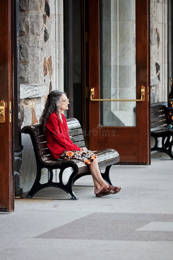 Elder lonely lady at her sixties sits on the bench of a station and waits for someone royalty free stock image Elder lonely lady at her sixties sits on the bench of a station and waits for someone royalty free stock image