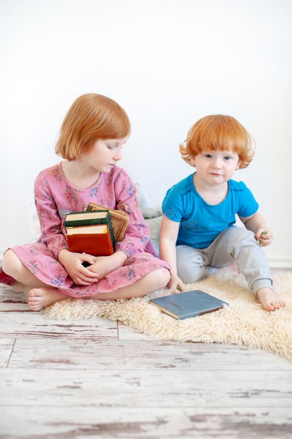 Брат читает книгу сестре. Старшая и младшая сестра читают книгу возле стеллажа. Read sister friends