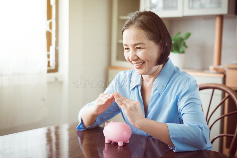 Elderly asian hands cover above piggy bank for retirement,Saving money concept