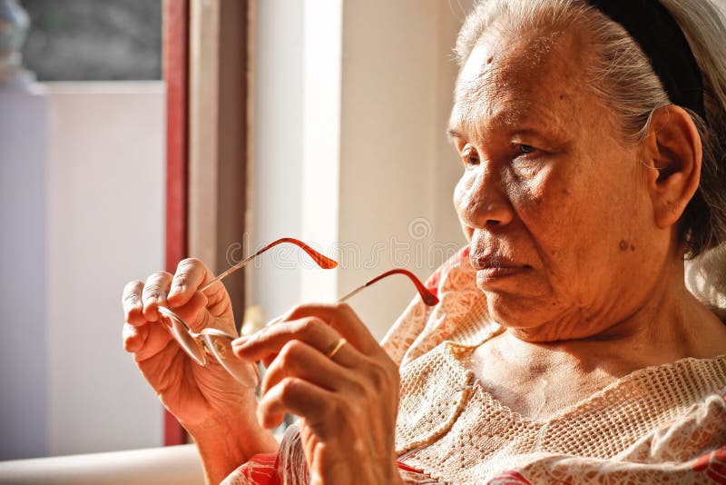 Elderly Asian Woman holding Glasses