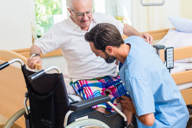 Elderly care nurse in retirement home helping senior from wheel chair to bed. Elderly care nurse in retirement home helping senior from wheel chair to bed