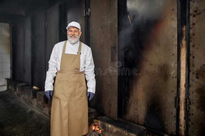 Elderly cheerful butcher, worker of smokehouse posing. stock image Elderly cheerful butcher, worker of smokehouse posing. stock image