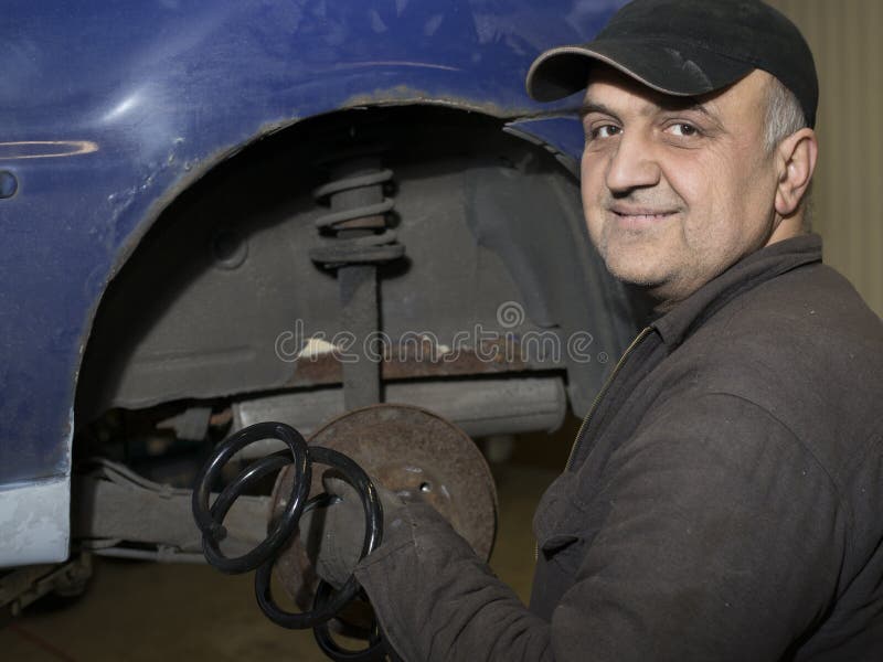 Elderly content mechanic fixing old car stock photo