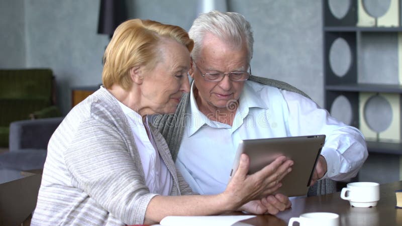 Elderly couple having fun in communicating with family on the internet in comfortable living room