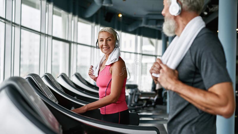 Elderly Couple Working Out On Treadmill In Fitness Center Stock Image