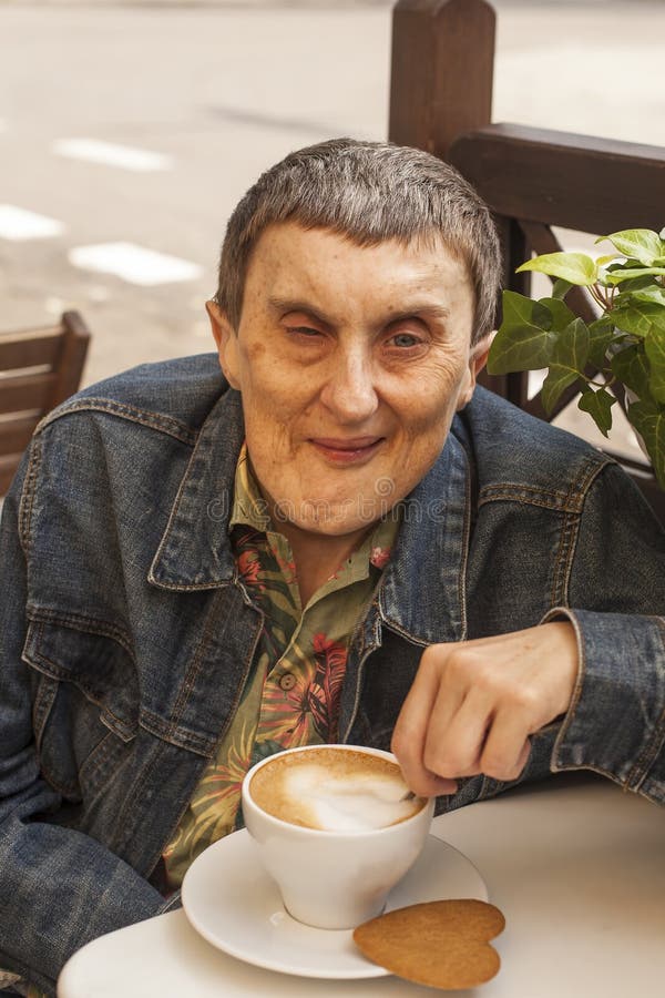 Elderly disabled man with cerebral palsy sitting at outdoor cafe royalty free stock images Elderly disabled man with cerebral palsy sitting at outdoor cafe royalty free stock images