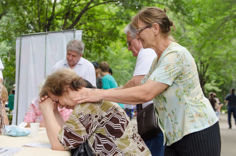 Elderly female volunteer doing relaxing massage to another elderly woman in park stock photography Elderly female volunteer doing relaxing massage to another elderly woman in park stock photography