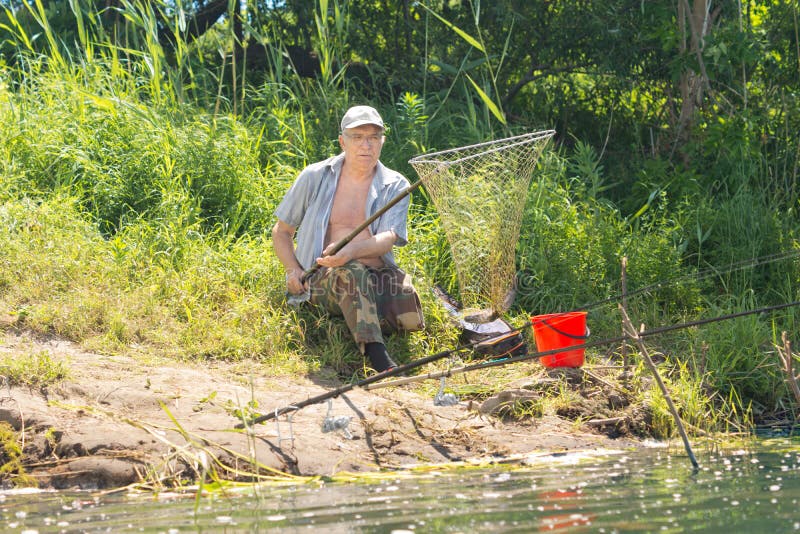 Elderly fisherman landing a fish in a fish net