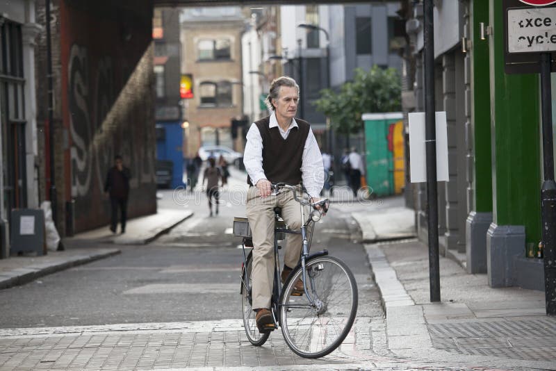 An elderly gentleman in a vest on a bicycle, turns on the main road royalty free stock images An elderly gentleman in a vest on a bicycle, turns on the main road royalty free stock images