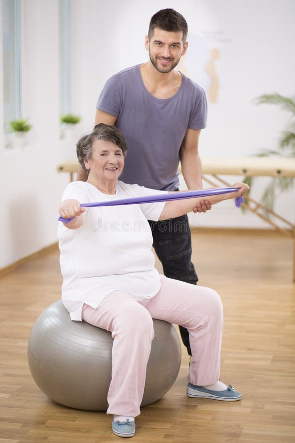 Elderly Siting on the Exercise Ball during Physiotherapy with Her Young