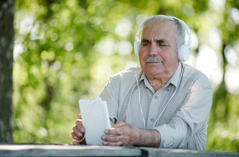 Elderly man listening to music on a tablet