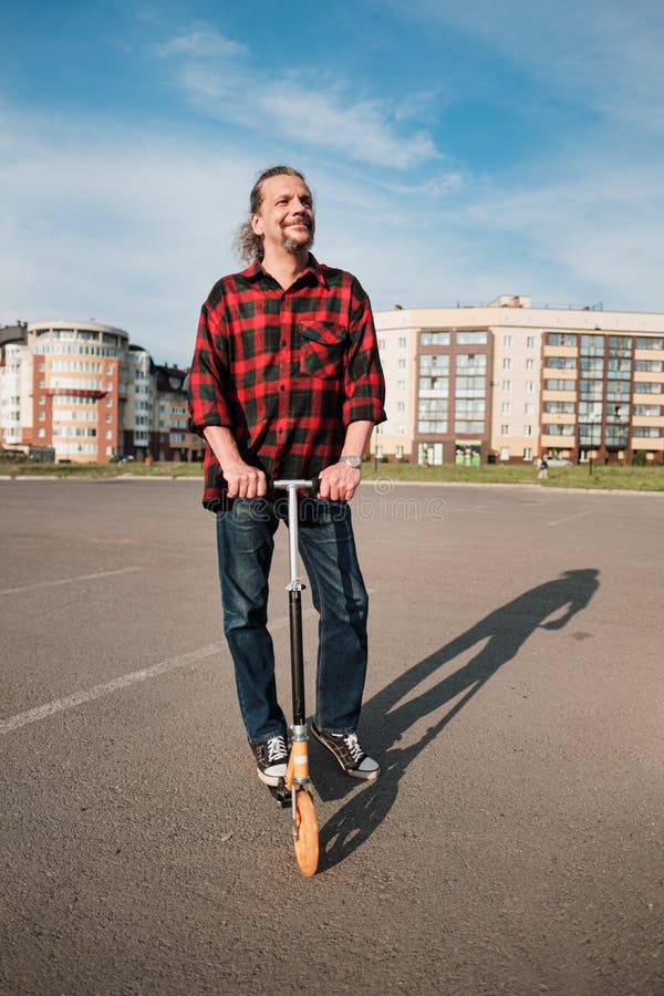 An Elderly Man with Long Hair and a Beard Rides a Scooter through the City  Streets. Check Shirt and Jeans Stock Image - Image of gadget, plaid:  150403003