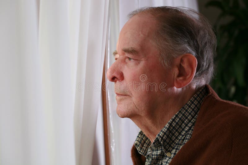 Senior man looking out of window in a loft flat stock photo